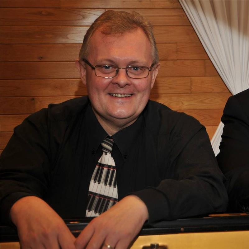 Lächelnder Mann mit Klavier-Halsband in Innenraum