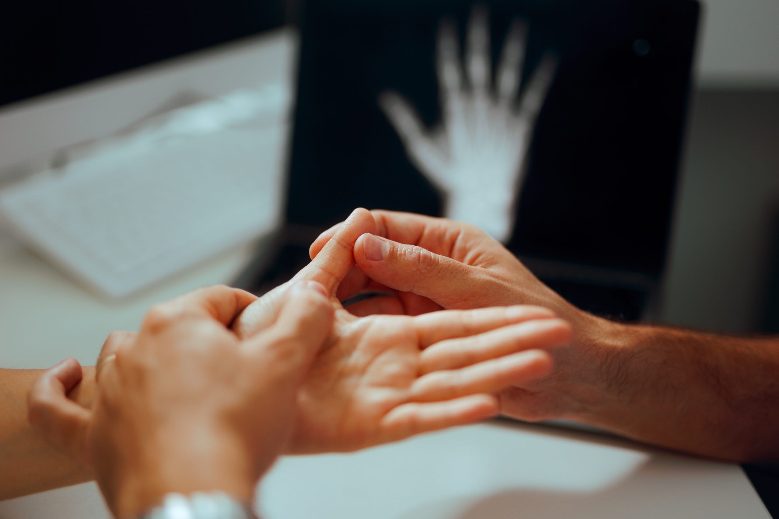 Zwei Hände, die sich bei einer Untersuchung treffen.