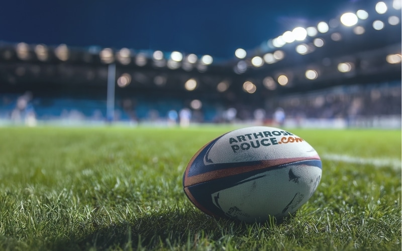 Rugbyball auf dem Grasfeld bei Nacht.