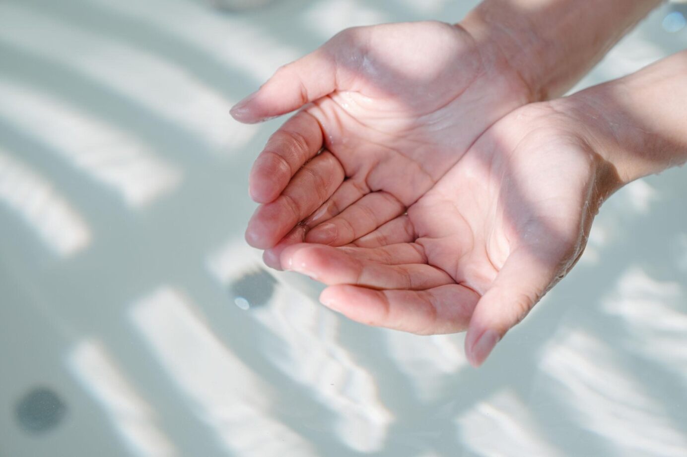 Hände halten Wasser in sanften Wellen.